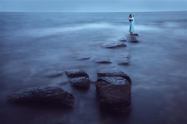 زن جوان زیبا در دریا در گرگ و میش قرار گرفتن در معرض طولانی مدت