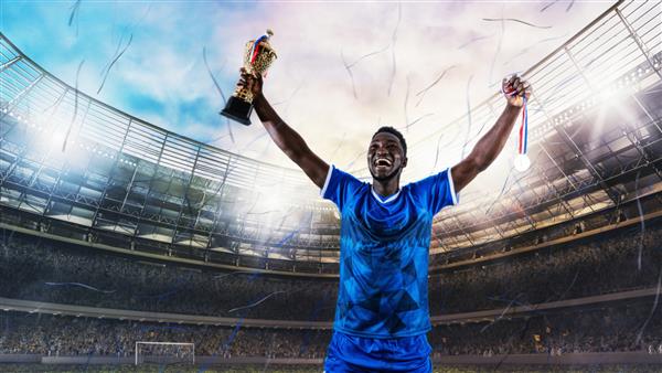 فوتبالیست با لباس آبی برای کسب یک جام در ورزشگاه شادی می کند