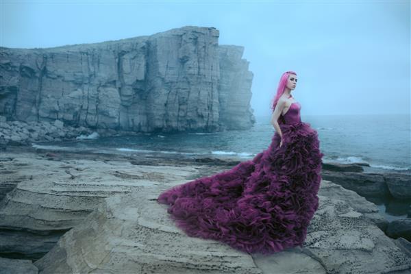 زنی با لباس بنفش که به دریای کوه نگاه می کند