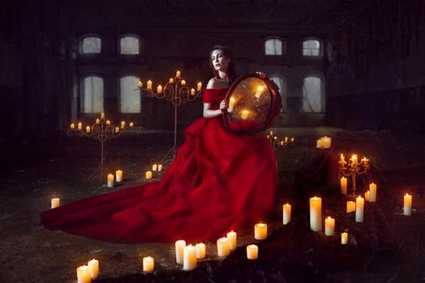 خانم زیبا با لباس مجلسی قرمز با شمع نشسته است