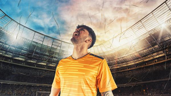 فوتبالیست با لباس زرد برای پیروزی در ورزشگاه شادی می کند