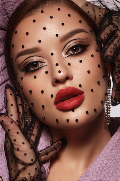 پرتره یک زن زیبا با مهره های سیاه آرایش خلاقانه روی صورتش در چهره زیبایی به سبک مد