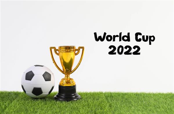 جام و توپ طلایی با متن جام جهانی 2022 روی چمن سبز