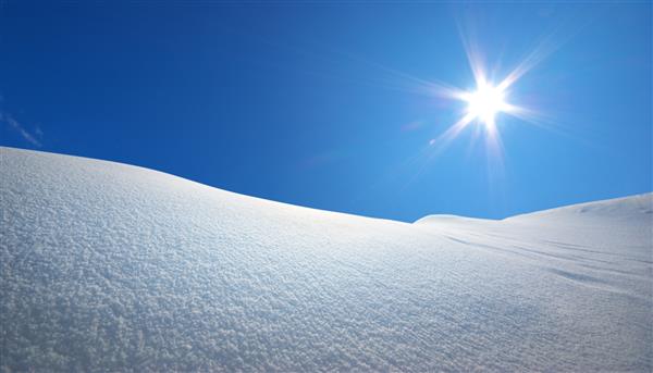 تپه های برفی و آسمان آبی عمیق در نور روز