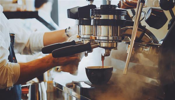 باریستا قهوه لاته آرت را با دستگاه اسپرسوساز به رنگ قهوه ای وینتیج درست می کند