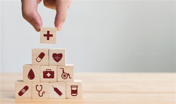 چیدمان دستی انباشته بلوک های چوبی با نماد مراقبت های بهداشتی پزشکی بیمه برای مفهوم سلامتی شما