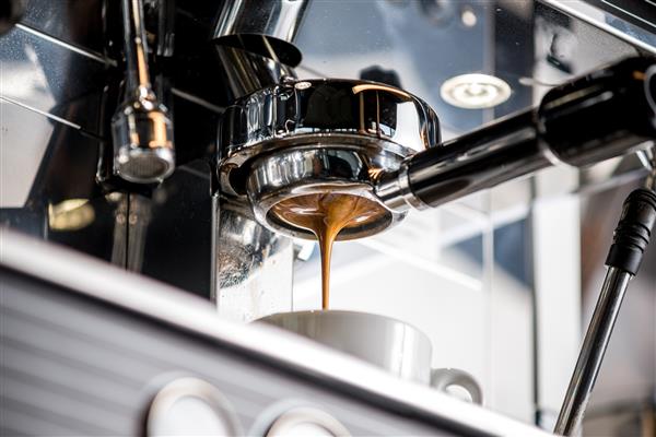 نمای نزدیک از ریختن اسپرسو از دستگاه قهوه ساز دم کردن حرفه ای قهوه