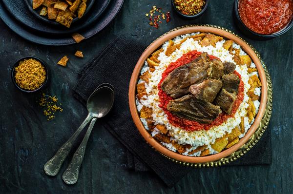 غذاهای عربی فتاح شرقی مصری با برنج سفید و نان ترد با سس قرمز سیر چاشنی شده سیر سرخ شده ترد و تکه های گوشت گوساله در زمینه تیره روستایی نمای بالا نمای نزدیک