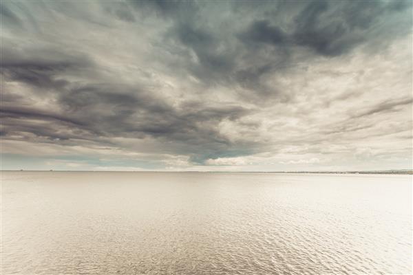 عکس ایده آل مینیمالیستی از آب دریا و آسمان افقی در طول روز ابری مفهوم زیبایی طبیعت