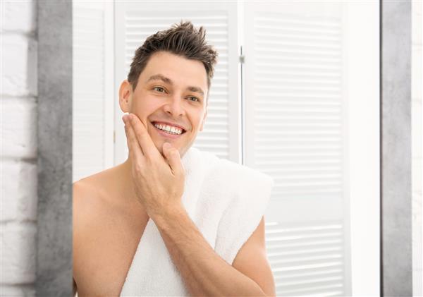 مرد خوش تیپ تراشیده نزدیک آینه در حمام