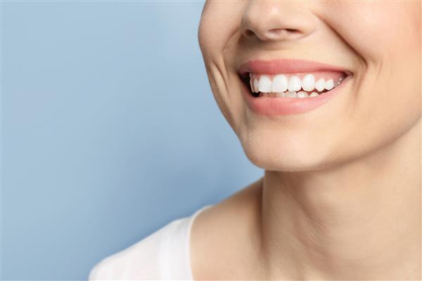 زن جوان با لبخند زیبا در زمینه خاکستری سفید کردن دندان