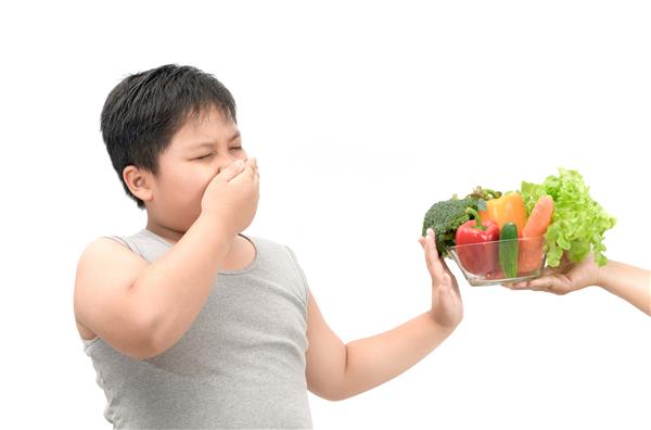 پسر چاق چاق با ابراز انزجار از سبزیجات جدا شده در پس زمینه سفید مفهوم غذا را امتناع می کند