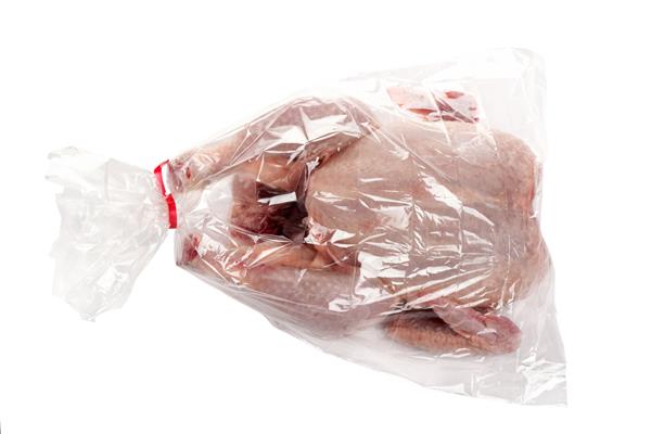 مرغ تازه و خام در یک کیسه پلاستیکی مخصوص فر روی پس زمینه سفید