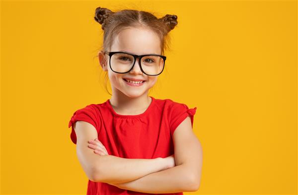 دختر بچه خنده دار با عینک روی پس زمینه رنگی