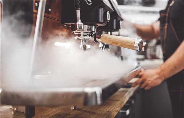 دستگاه قهوه در بخار باریستا در حال تهیه قهوه در کافه