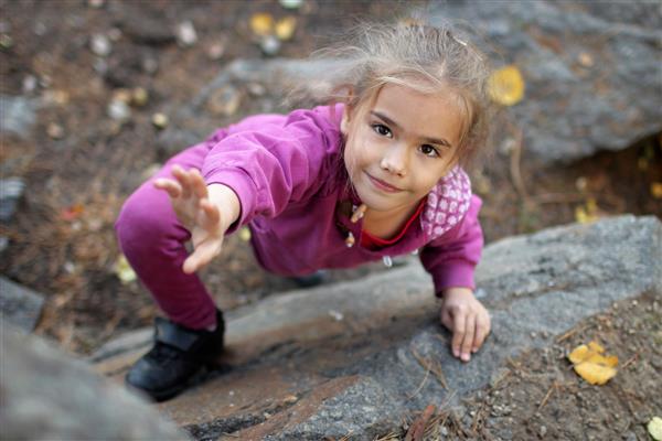 یک دختر کوچولوی ناز که به ورزش های صخره نوردی ورزش های شدید در فضای باز و سبک زندگی فعال کوه های صخره ای طبیعی مشغول است