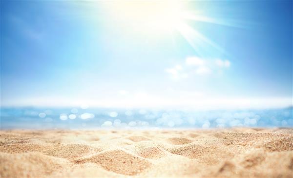 پس‌زمینه بدون تمرکز تاری انتزاعی طبیعت ساحل تابستانی گرمسیری با پرتوهای نور خورشید ساحل شنی طلایی آب دریا در برابر آسمان آبی با ابرهای سفید فضای کپی مفهوم تعطیلات تابستانی