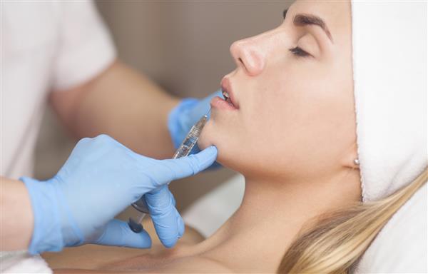 متخصص زیبایی سم بوتولینوم را در لب های بیمار تزریق می کند مراقبت از پوست زیبایی تزریق فیلر لب