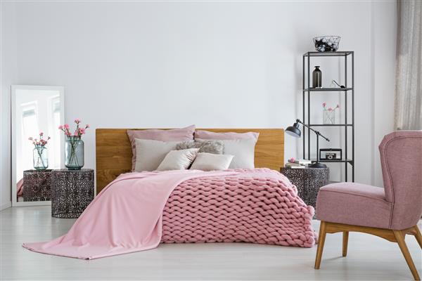 پتو و لحاف پشمی دنج صورتی روی تخت خواب کینگ راحت در فضای داخلی اتاق خواب شیک