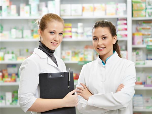 دو زن شیمیدان داروساز شاد در داروخانه داروخانه ایستاده اند