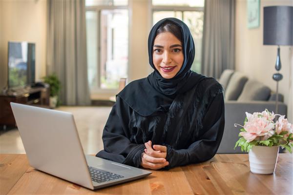 زن جوان تاجر عربی با حجاب با لپ تاپ در خانه