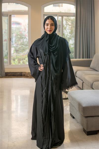 پرتره تمام قد از زن جوان مسلمان با حجاب که در خانه ایستاده است