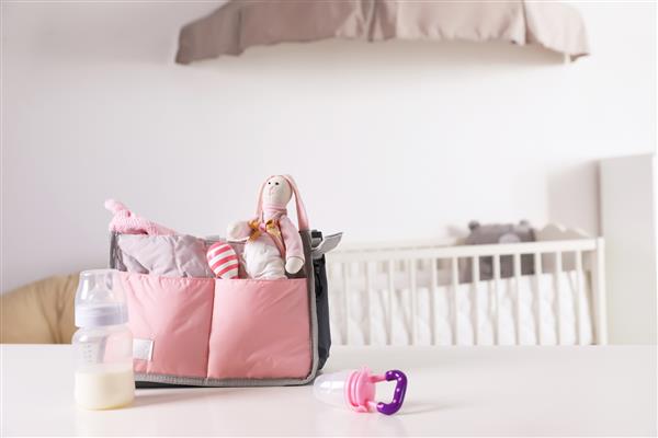 کیف بارداری با لوازم کودک روی میز داخل خانه فضایی برای متن