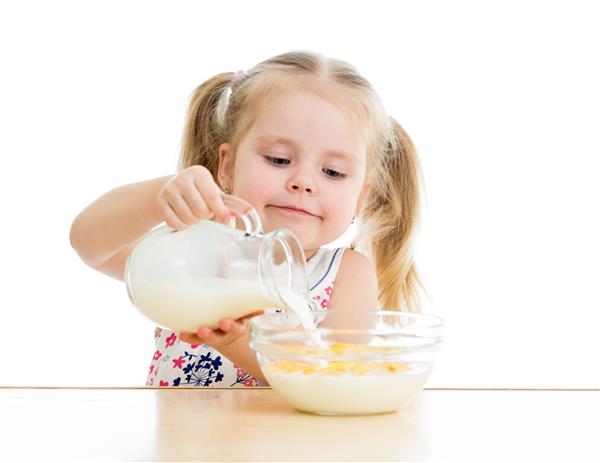 دختر بچه در حال تهیه دانه های ذرت با شیر