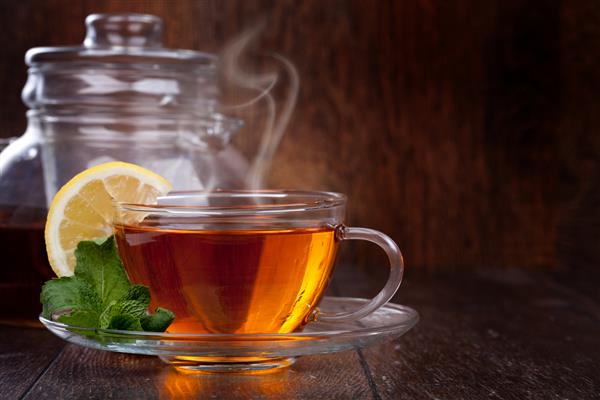 فنجان چای با نعناع و لیمو در زمینه چوبی