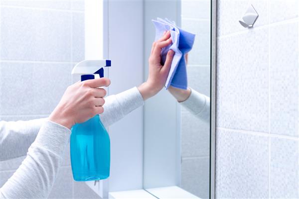 تمیز کردن و جلا دادن آینه با پارچه و اسپری در حمام در منزل خدمات خانه داری و نظافت خانه تمیز تمیزی