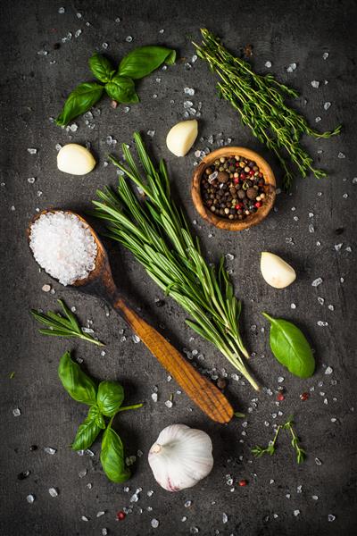 گیاهان و چاشنی ها روی میز سنگ سیاه رزماری ریحان آویشن لیمو نمک دریا و غیره نمای بالا با فضای کپی