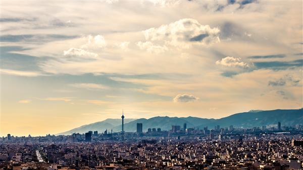 خط افق تهران در یک روز ابری زیبا با نور ساعت طلایی منظره شهری تهران-ایران با برج میلاد در عکس و ابرهای سفید و آسمان آبی دوست داشتنی