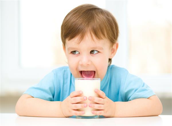 پسر بچه ناز زبانش را در لیوان شیر فرو می برد
