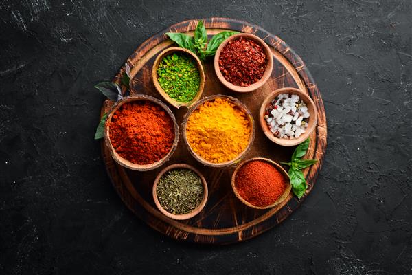گیاهان و ادویه های رنگارنگ برای پخت و پز ادویه های هندی در زمینه سنگ سیاه نمای بالا