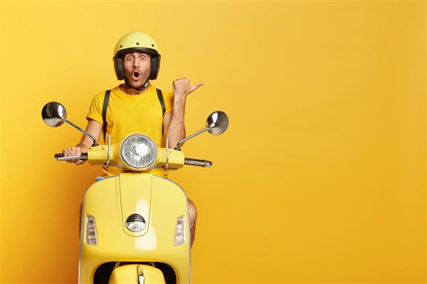 راننده تحت تاثیر با موتورسیکلت زرد مسافت را طی می کند کلاه ایمنی می پوشد با تعجب زیاد نشان می دهد در جاده توقف می کند فضای خالی برای محتوای تبلیغاتی شما نشان می دهد وسیله نقلیه جدید را امتحان می کند