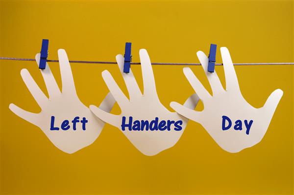 پیام تبریک روز چپ دست‌ها در کارت‌های شبح دست چپ که از گیره‌ها روی یک خط در مقابل پس‌زمینه زرد آویزان شده‌اند برای روز جهانی چپ‌دست‌ها در 13 اوت