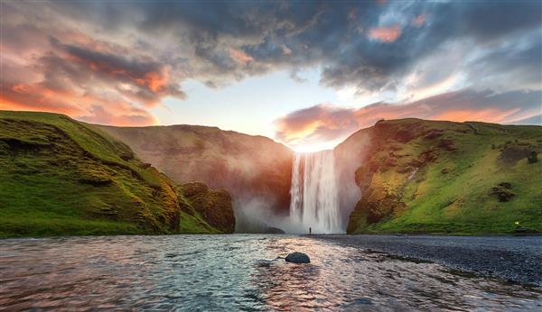 منظره ایسلندی نمای کلاسیک با نوردهی طولانی از آبشار معروف اسکوگافوس با آسمان رنگارنگ در هنگام غروب آفتاب رودخانه اسکوگا ارتفاعات ایسلند اروپا مقاصد محبوب سفر طبیعت شگفت انگیز