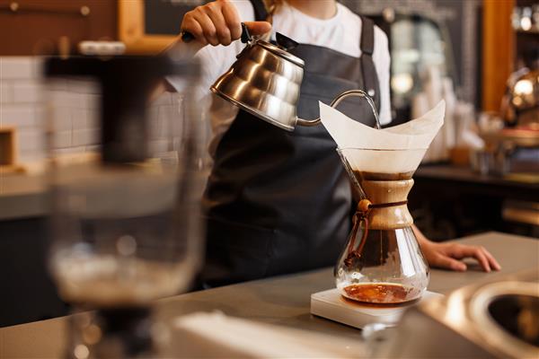 باریستای حرفه ای قهوه را با استفاده از chemex بر روی قهوه ساز و کتری قطره ای آماده می کند روش های جایگزین برای دم کردن قهوه مفهوم کافی شاپ