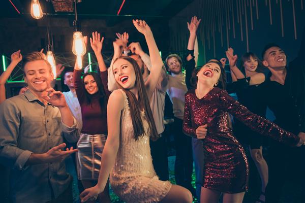 عکس گروه بزرگی از دانش‌آموزان که برای تفریح و رقص با هم با حالات چهره هیجان‌زده و نورهایی که در بالا می‌درخشند وارد باشگاه شبانه شده‌اند