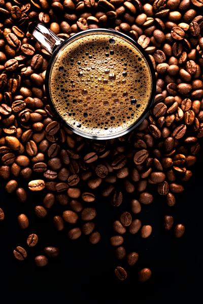 اسپرسو با فوم قهوه در فنجان روی پس زمینه تیره از دانه های قهوه نمای بالا فوکوس انتخابی فضای کپی