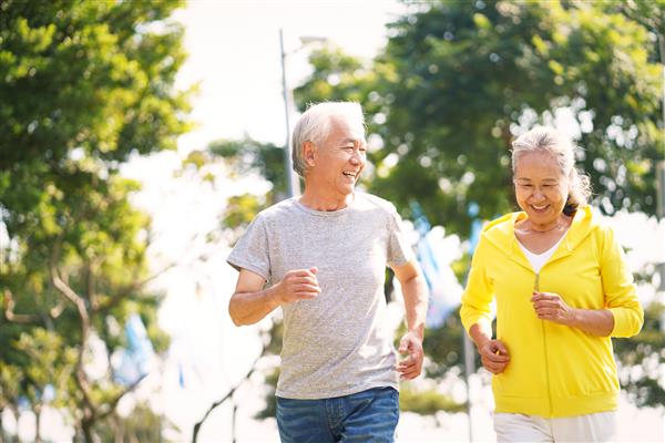زوج مسن آسیایی شادی که در حال ورزش کردن در فضای باز در پارک هستند