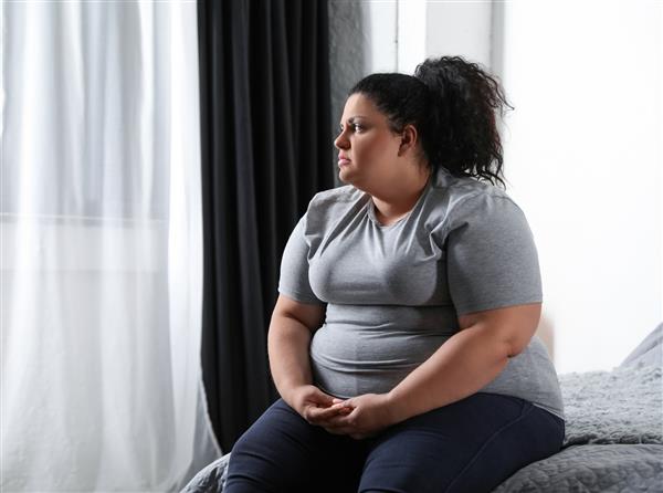 زن افسرده دارای اضافه وزن روی تخت در خانه