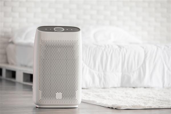 تصفیه کننده هوا در اتاق خواب سفید دنج برای فیلتر و تمیز کردن از بین بردن گرد و غبار PM2 5 HEPA در خانه برای هوای تازه و زندگی سالم مفهوم آلودگی هوا