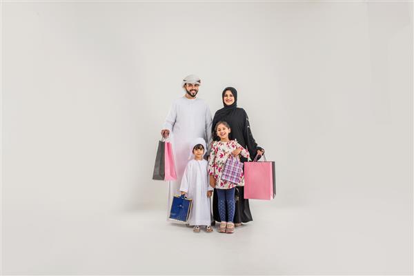 خانواده خاورمیانه با لباس های سنتی اماراتی که در یک استودیوی عکاسی ژست می گیرند - مفاهیمی درباره سبک زندگی شادی و روابط خانوادگی در امارات
