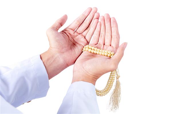 مرد مسلمان در حال نماز با مهره های نماز بر روی دست هایش جدا شده روی پس زمینه سفید
