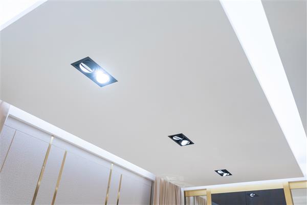 به سقف کاذب با لامپ های هالوژنی و ساخت دیوارهای خشک در اتاق خالی آپارتمان یا خانه نگاه کنید سقف کشسان سفید و شکل پیچیده