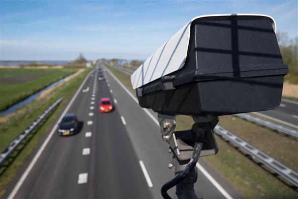 دوربین مدار بسته امنیتی یا سیستم نظارت ترافیک وسایل نقلیه را در جاده ای در هلند با تاری عمدی در پس زمینه مشاهده می کند