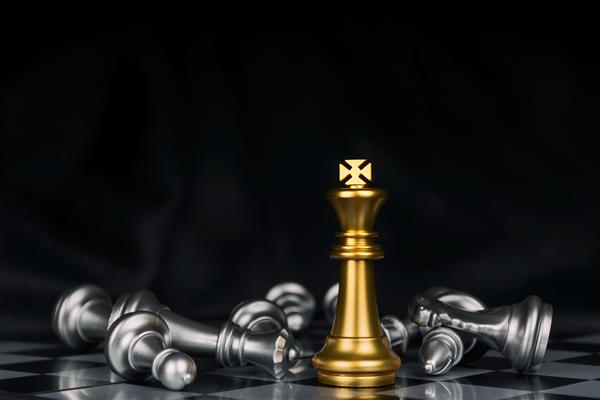 برنده شات پادشاه طلایی احاطه شده با مهره های شطرنج نقره ای در مسابقه بازی شطرنج با پس زمینه تیره نبرد شطرنج پیروزی موفقیت رهبر تیم کار تیمی مفهوم استراتژی تجاری