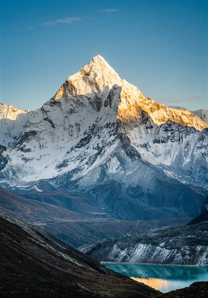 تصویر عمودی قله کوه آمادابلام در هنگام غروب آفتاب و نمایی از دریاچه یخچالی Cholatse در دامنه کوه‌های منطقه اورست نپال