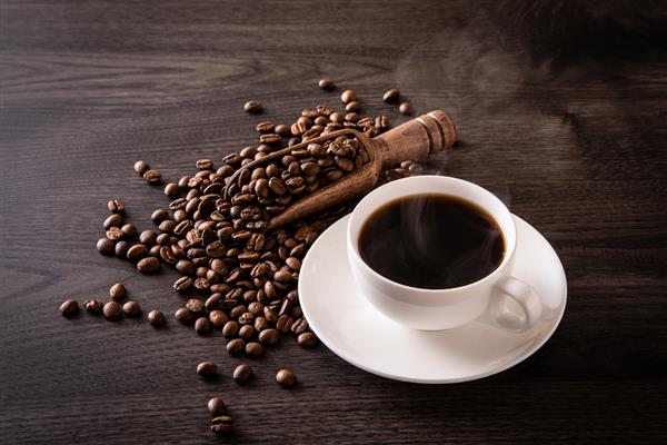 دانه های قهوه و قهوه داغ روی میز